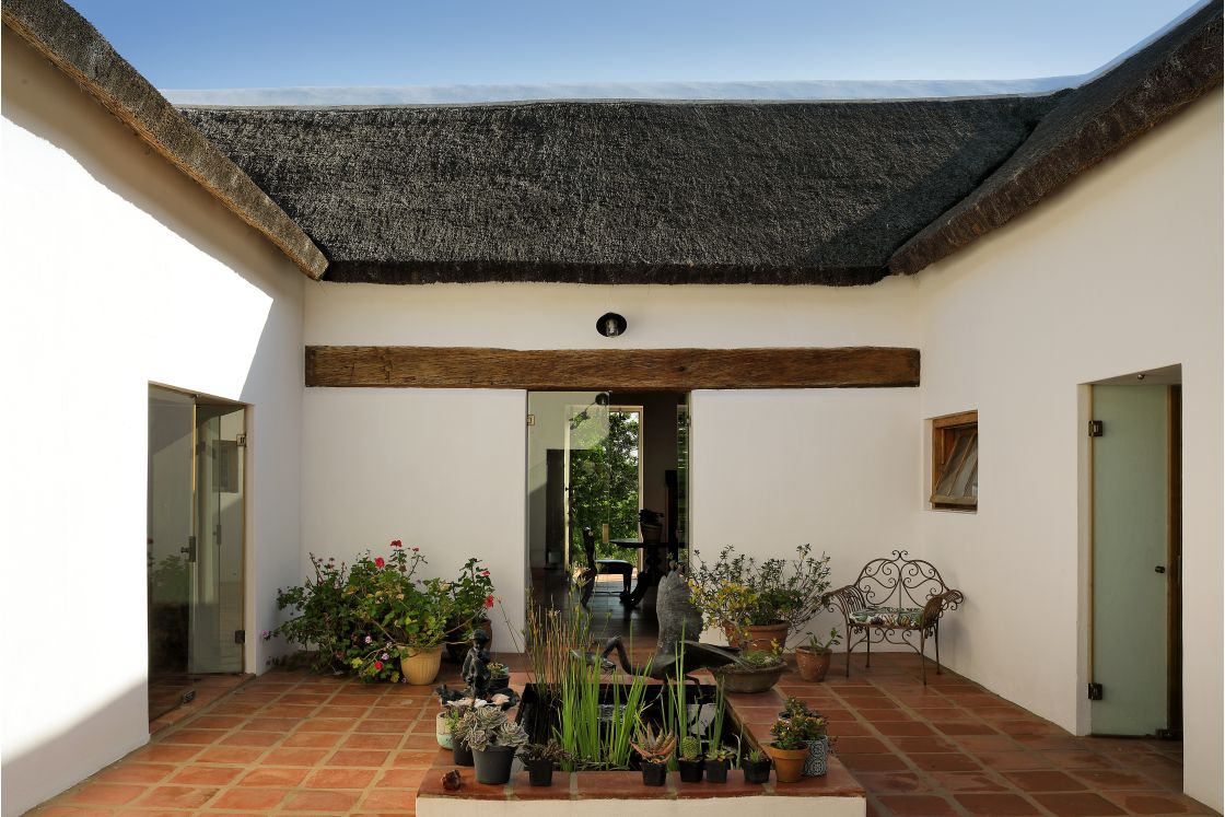 Central courtyard featured in the Cape-Dutch style. A rectangular pond in the center, with small decorative plants.