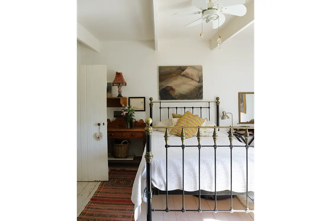 Perfect Hideaways real estate property: Bedroom with a neutral color and black and gold decorative steel bed frame. The White House in Barrydale.