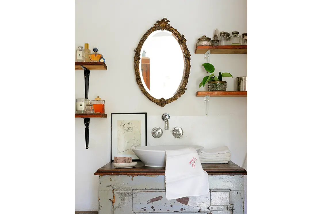 Perfect Hideaways real estate property: Ornate mirror above basin cabinet with aged paintwork, and wooden shelving for bathroom essentials. The White House in Barrydale.