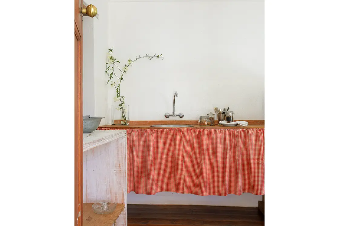 Perfect Hideaways real estate property: Wooden counter space with sink and prep station, chequered curtain hangs from the countertop. The White House in Barrydale.