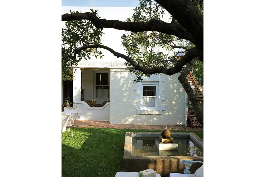 Perfect Hideaways real estate property: Outdoor seating area beside garden water feature with heritage home in the background. The White House in Barrydale.