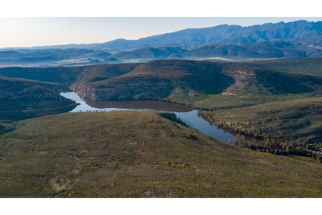 A river on the plot of land for sale, featuring multiple tributaries and a landscape view of the mountain ranges in the background.