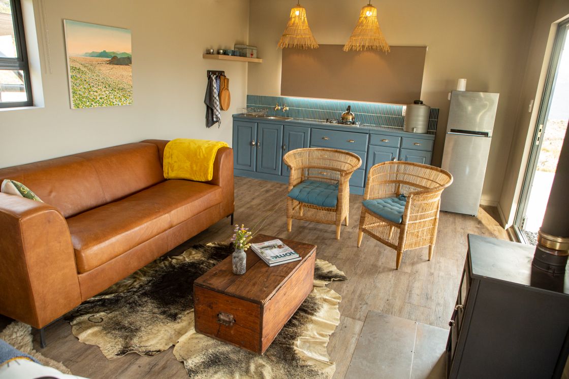 A living area, featuring a functional kitchen with blue cupboards and backsplash, an indoor fireplace, and a comfortable seating area.