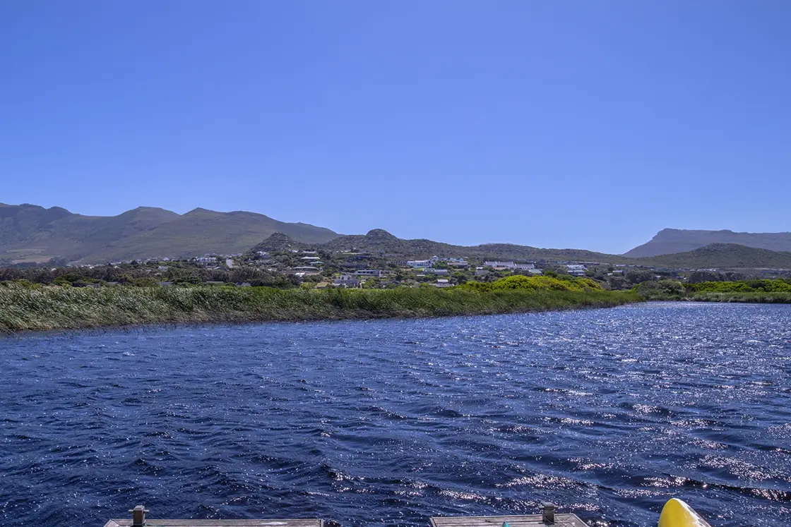 Perfect Hideaways property for sale: A body of water in the saltwater wetland, as seen from a dock near the residence. Residential properties near the iconic ‘Chapman’s Peak’ are visible across the wetland. Waterside. Noordhoek.