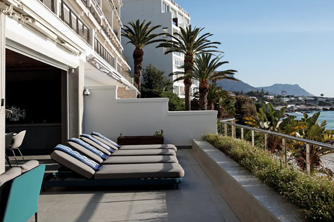 Perfect Hideaways property for sale: The balcony area of the apartment, which has multiple sun chairs, and showcases the immediate proximity of one of Cape Town’s famous blue flag beaches. San Michelle, Clifton.